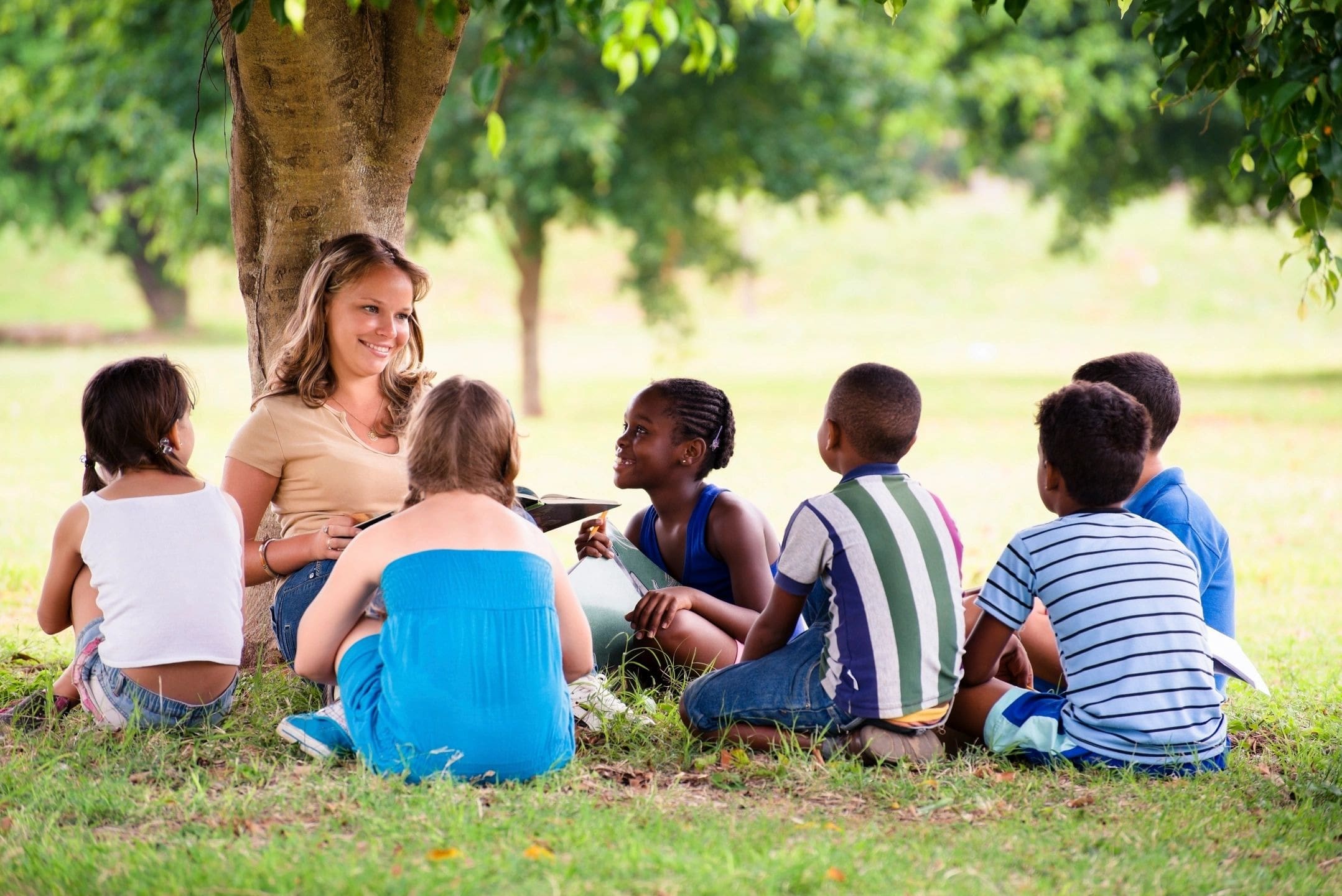 A group of children sitting around in the grass.