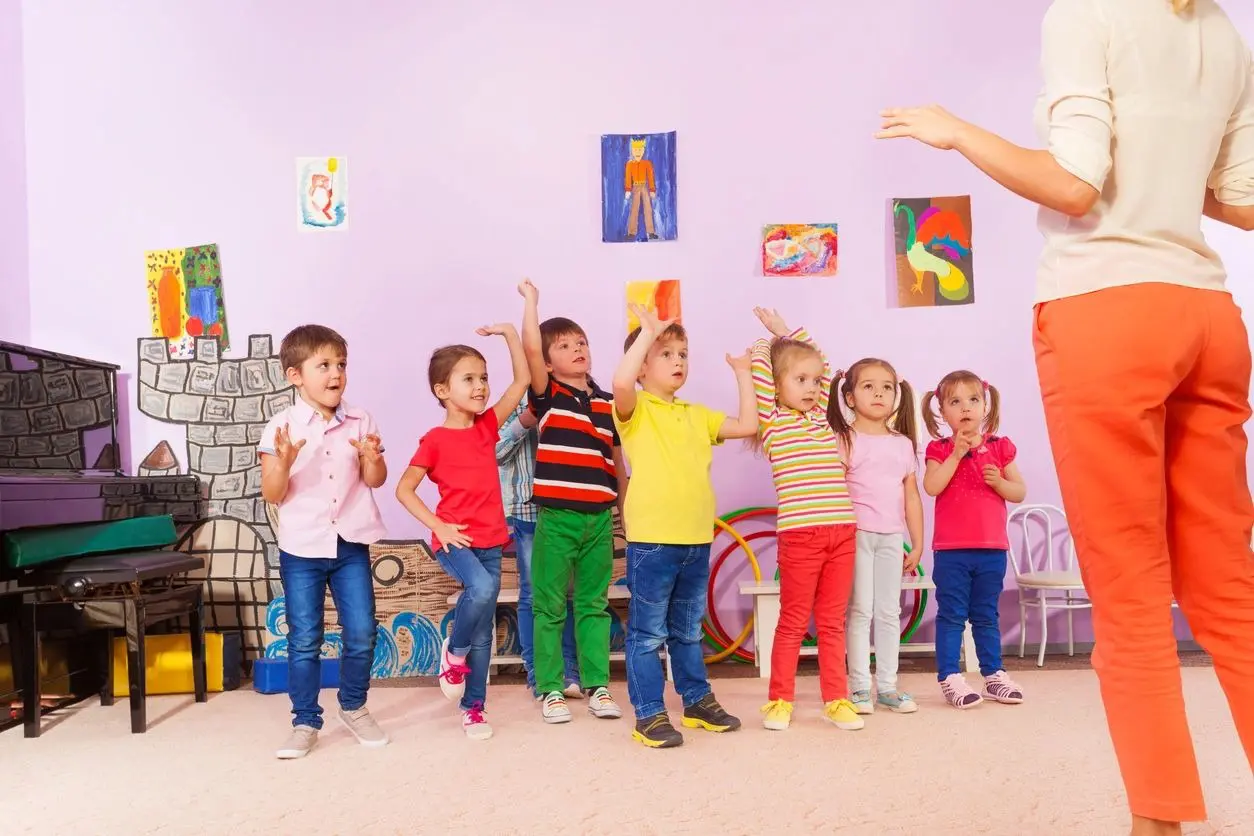 A group of children standing in front of an adult.