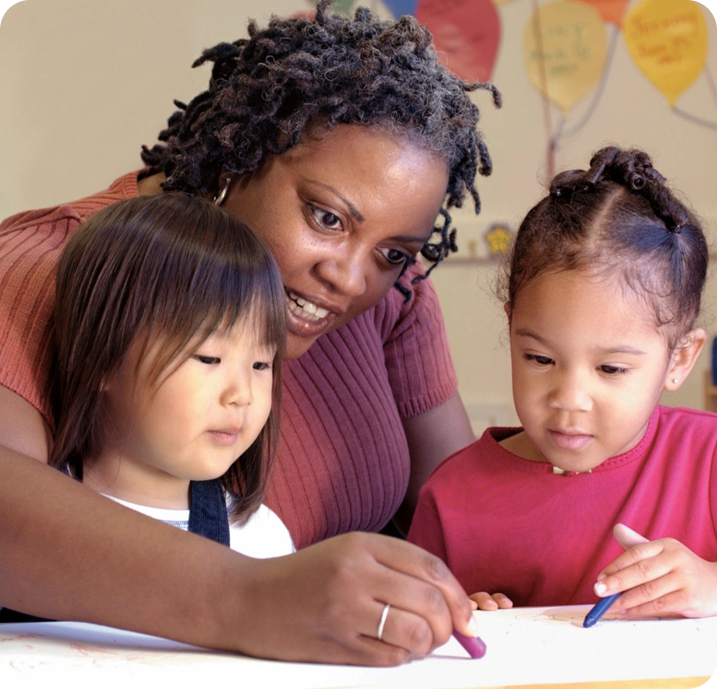 A woman and two children are writing on paper.